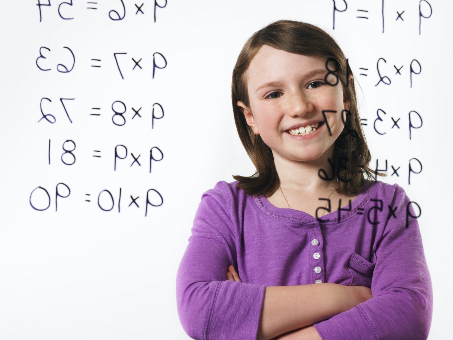 A child looking at a series of multiplication tables written on a see through surface.