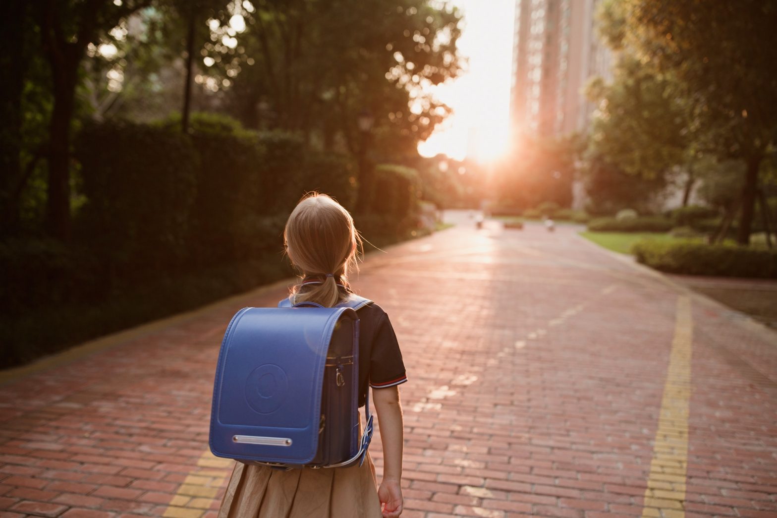 Schoolgirl back to school. Pupil in uniform and backpack outdoor