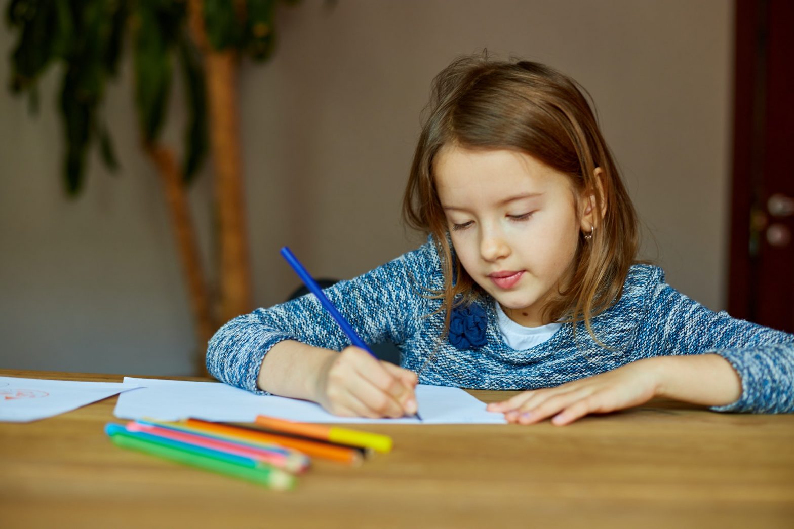 School girl drawing and writing a picture with crayons, using colored pencils