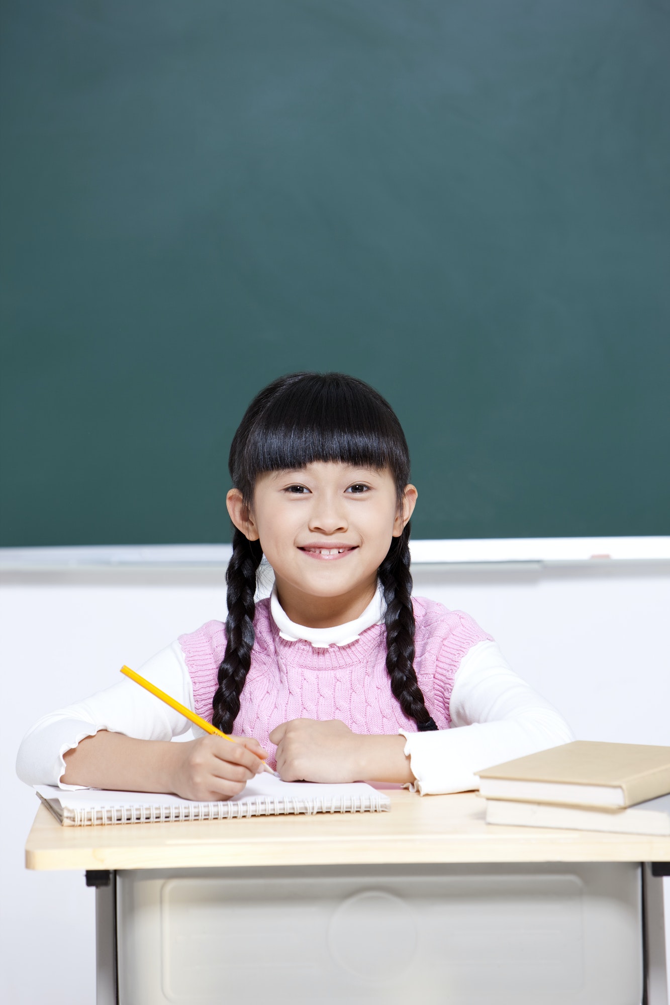 Cheerful schoolgirl writing in classroom