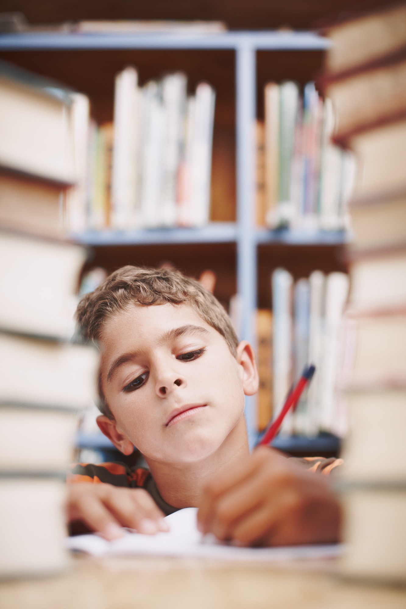 Hmmm...A young boy doing some creative writing between a stack of books.