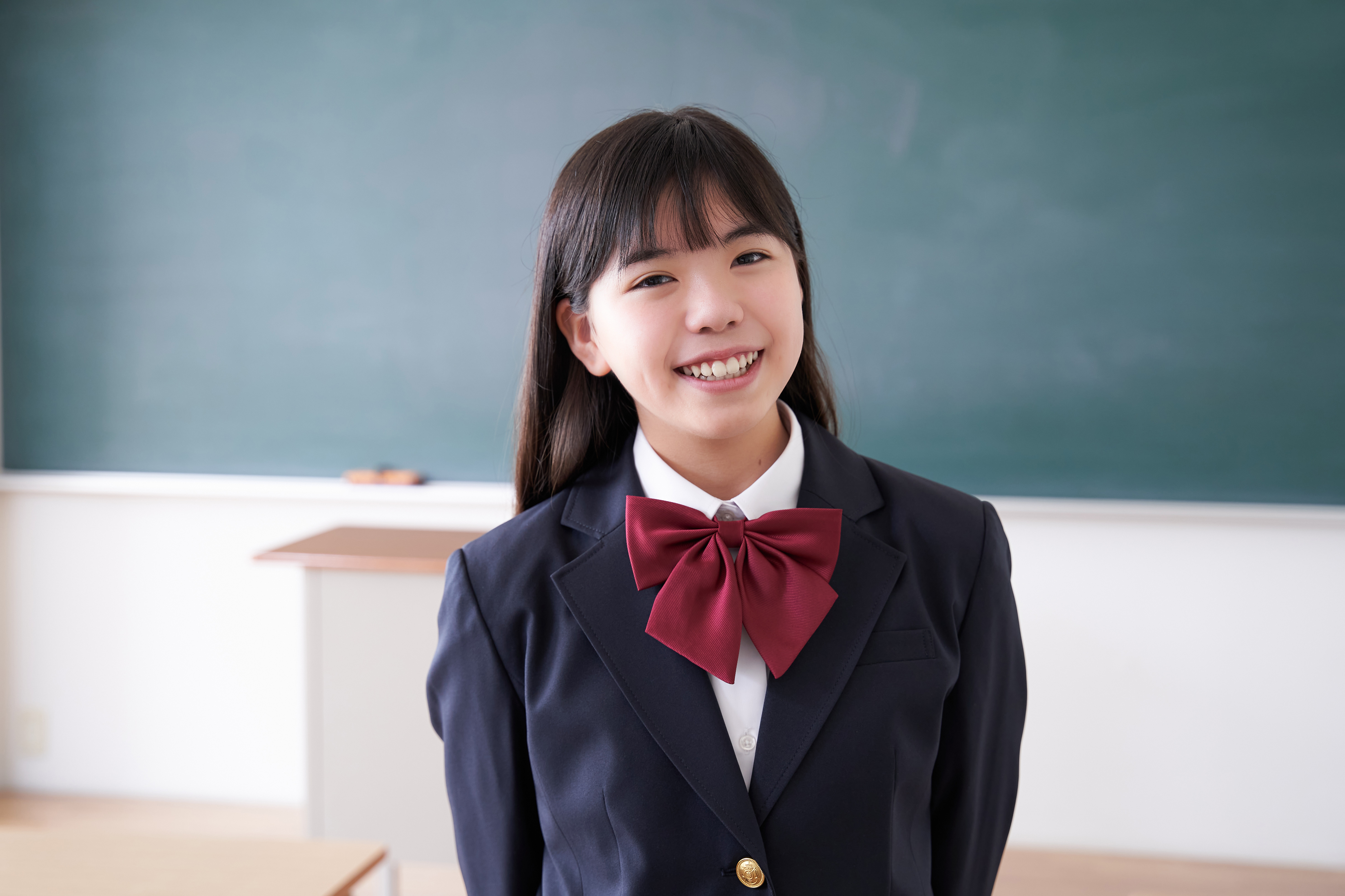 A Japanese junior high school girl stands in the classroom with a smile