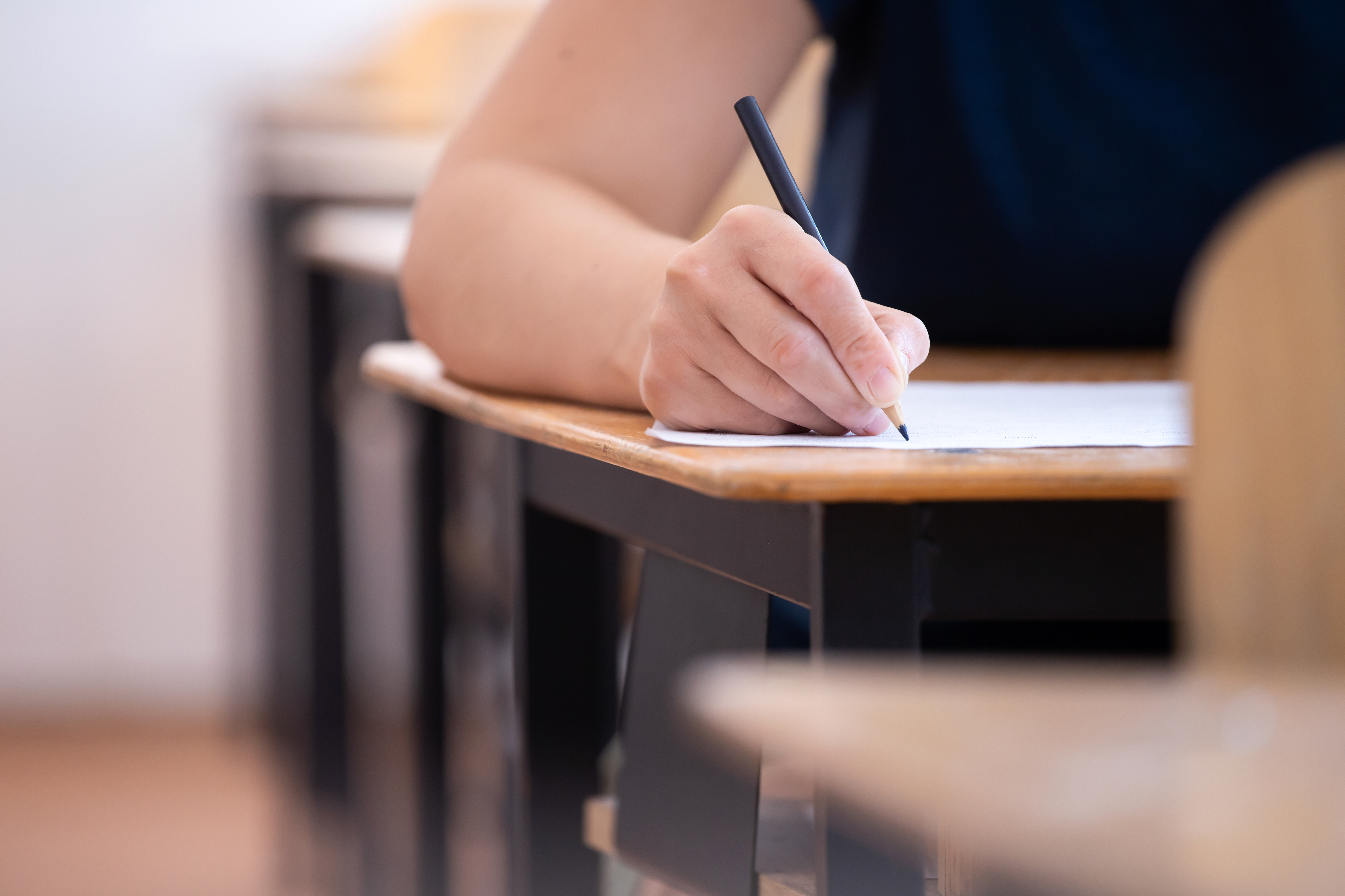 Student writing final exam in classroom.